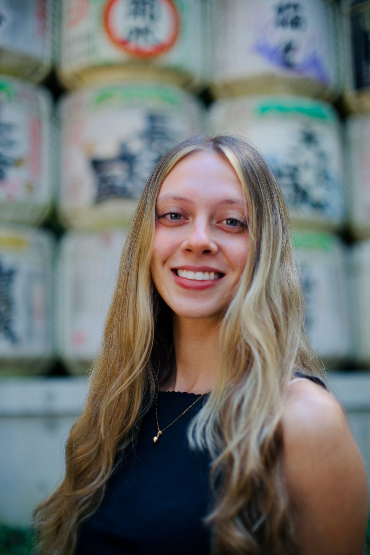 A young woman in front of the sake barrels at Meiji Jingu