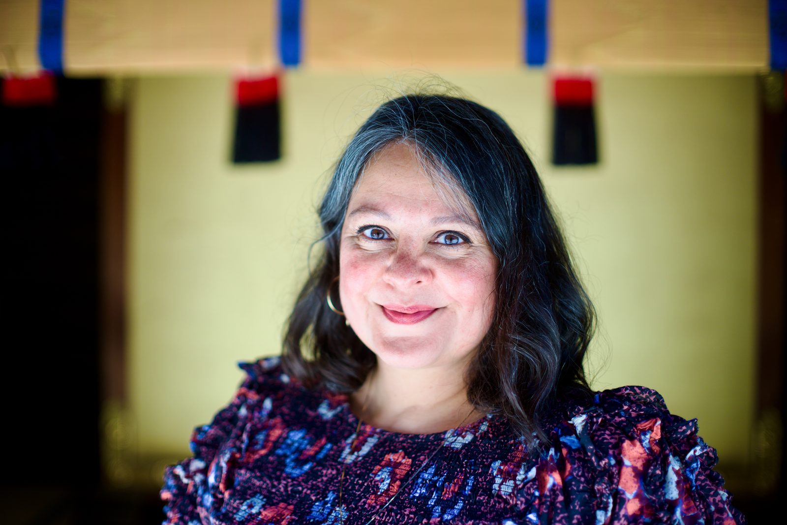 A woman smiling in front of the shrine curtains